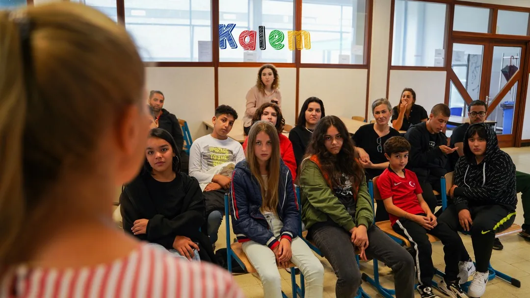 Jongeren en volwassenen luisteren naar een spreker in een klaslokaal.