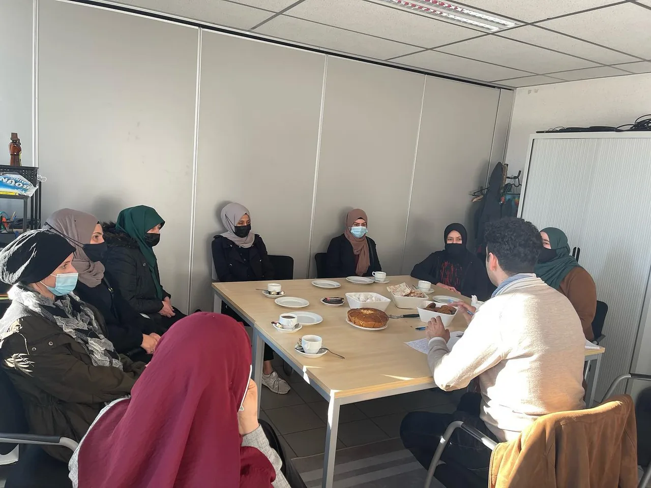 Een groep volwassenen praat rond een tafel tijdens een toelichting over Project Anne.